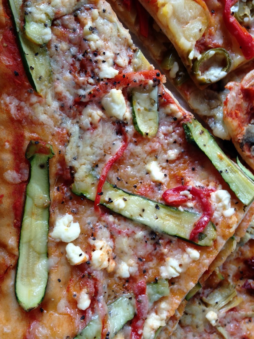 Slices of vegetable focaccia topped with courgette, red pepper, feta and cracked black pepper